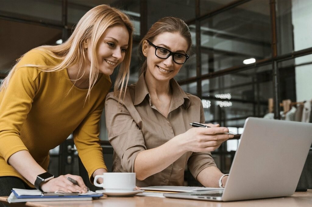 A picture of two women at work looking at a laptop.